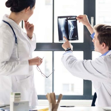 Experienced orthopedist helping his colleague with the interpret